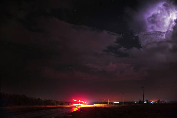 A breathtaking night scene showcasing vibrant lightning, dramatic clouds, and beautifully illuminated roads ahead