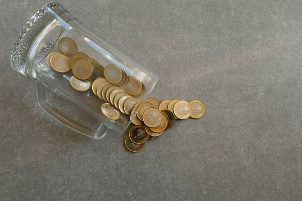 Euro coins spilling out a money jar on white background.