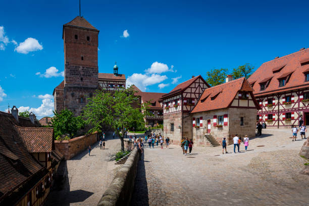 Nuremberg, Germany - May 20, 2024:  Some people walking in the historic old castle with half-timbered houses and tower.