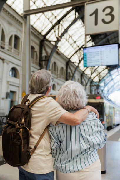 istock Senior couple embracing and checking train schedule in station 2188571538