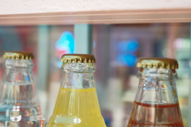 Close-up of assorted vintage beverage bottles featuring colorful caps in a bar or shelf setting.