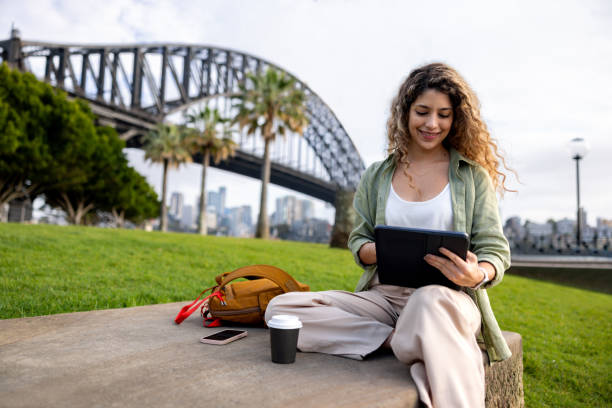 istock Woman working outdoors on her tablet in Sydney while drinking coffee 2188580369