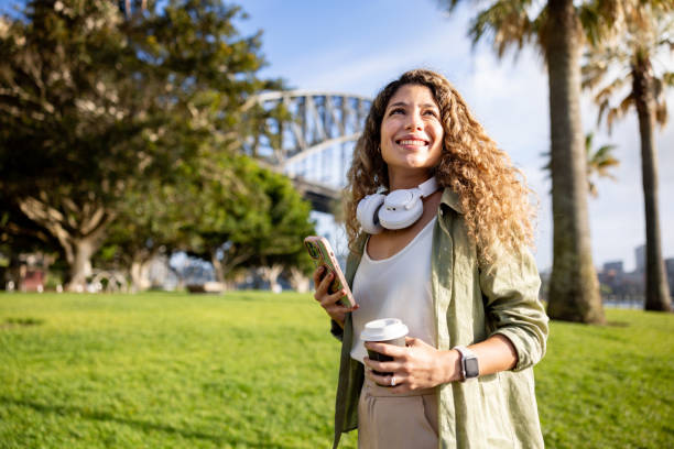 istock Woman walking outdoors drinking coffee and using her cell phone 2188580389