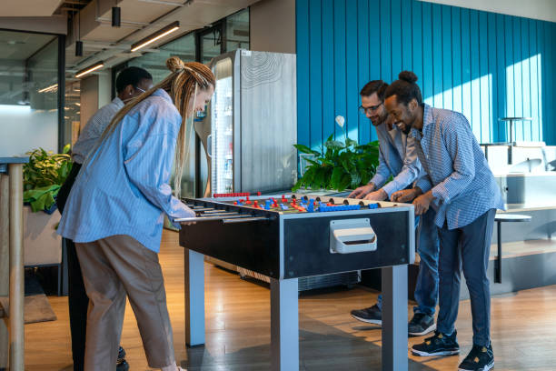 A group of young professionals enjoy a lively foosball game in a modern office setting, fostering teamwork and camaraderie during a break from work.