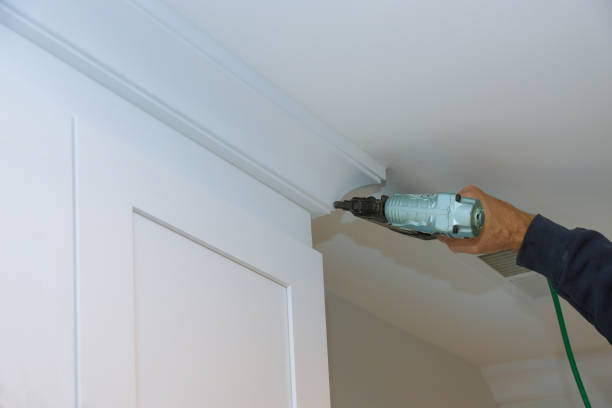 istock Home renovation project in progress as worker installs crown molding using power air gun 2188581840