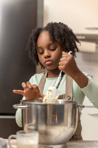 Beautiful young black girl preparing a xmas cake alone
