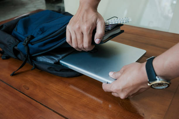 istock Closeup of hand man holding laptop on inside Blue backpack with books and notepad inside for student or working 2188598482