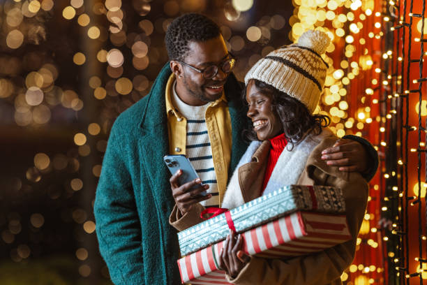 istock Couple enjoying a festive Christmastime evening outdoors and using a smartphone 2188601478