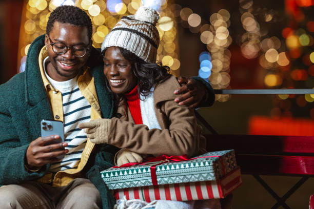 istock Couple enjoying a festive Christmastime evening outdoors and using a smartphone 2188601636