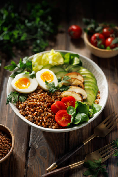 istock Buckwheat groats with avocado, various vegetables and soft-boiled egg in a ceramic bowl on a wooden table, close-up. 2188601998