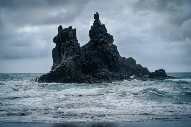 istock A dark rocks amist stromy wavy ocean in a cloudy weather. 2188602660