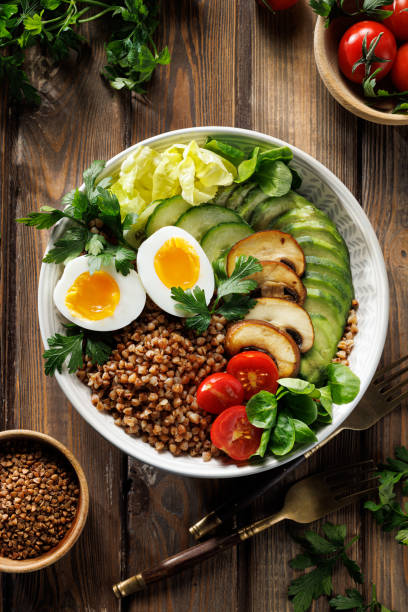 istock Buckwheat groats with avocado, various vegetables and soft-boiled egg in a ceramic bowl on a wooden table, top view. 2188603744