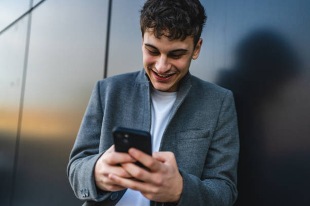 istock young cheerful man use mobile phone in front black wall outdoor 2188603821