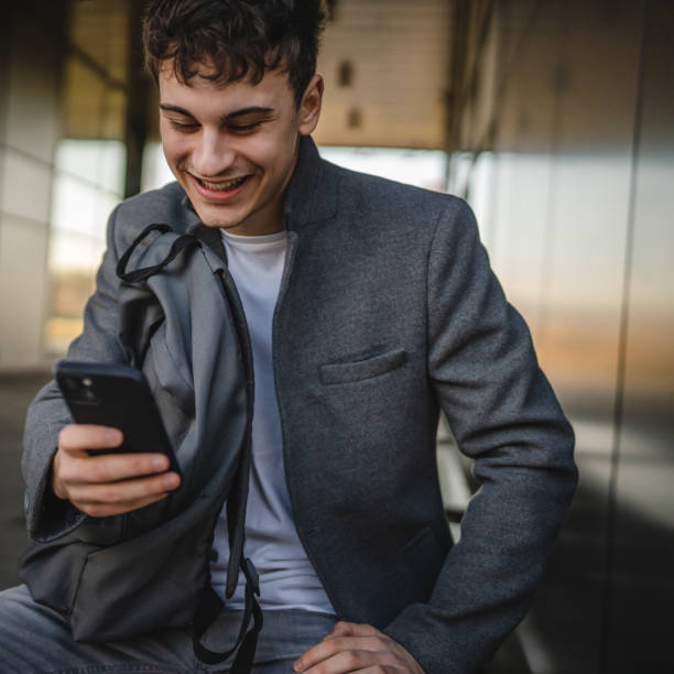 istock young man sit on bench with backpack and use mobile phone on break 2188605025