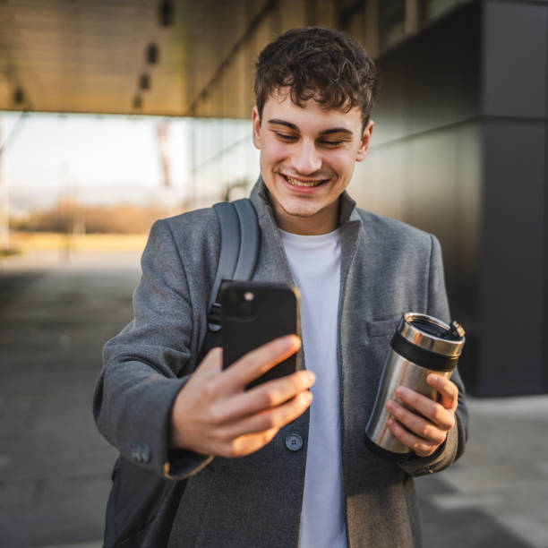 istock young man drink coffee walk from work and have video call on cellphone 2188605331