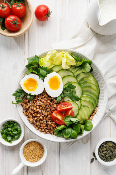 istock Buckwheat groats with avocado, various vegetables and soft-boiled egg in a ceramic bowl on a white table, top view. 2188606983