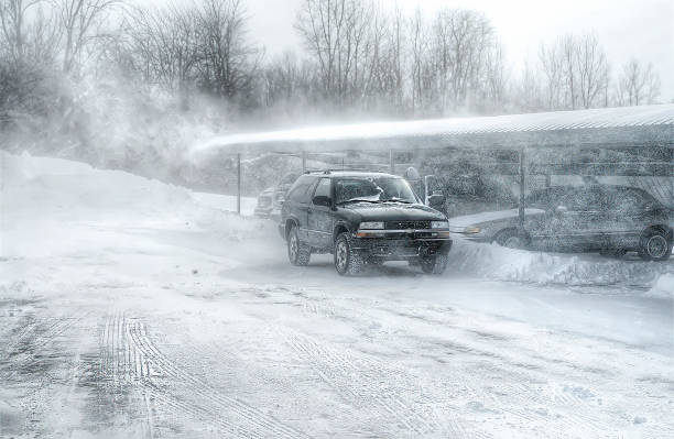 On a cold February morning, heavy wind blows snow over a carport and onto a stalled car in Mason, Michigan.