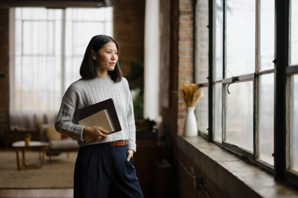 Professional Woman Standing in Modern Office Holding a Tablet