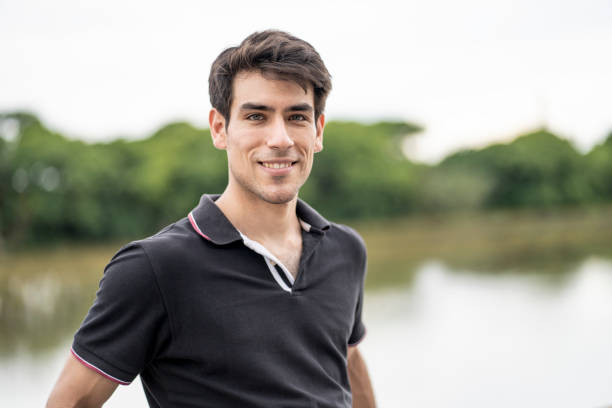 Portrait of smiling young man looking at camera while walking along a river