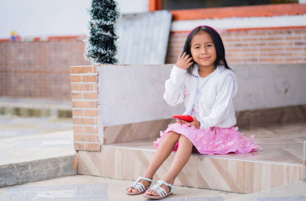 Colombian indigenous girl sitting outside her casual home and looking at the camera
