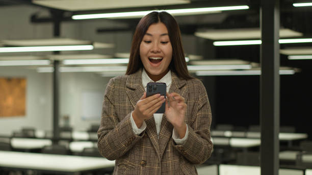 istock A woman is standing in an office space while looking down at her cell phone 2188624290