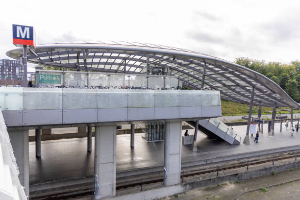 Futuristic metro station with steel and glass architecture. Passengers wait at platform under large curved roof. Urban transit hub with contemporary design elements.