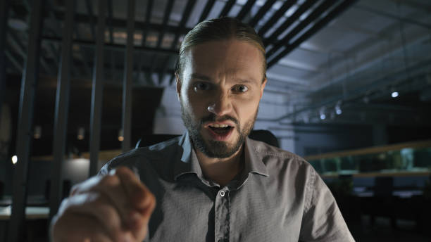 Business contract problem report mistake Caucasian angry aggressive yelling scolding businessman at dark evening office annoyed employee man talking shouting at camera video call with papers documents. High quality 4k footage