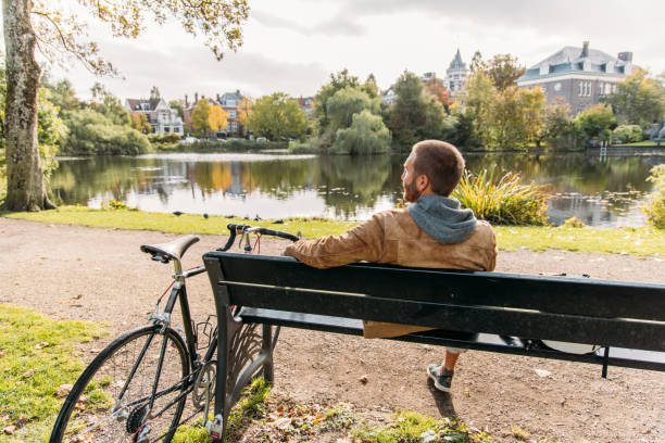 istock Man with a bicycle sitting on public park bench in Amsterdam 2188633633
