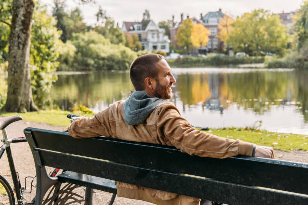 istock Man with a bicycle sitting on public park bench in Amsterdam 2188633641