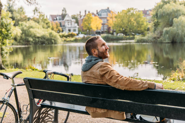istock Man relaxing on park bench by a serene lake with bicycle nearby 2188633653