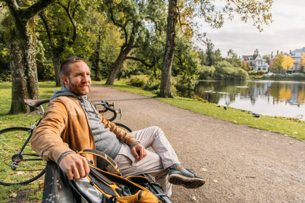 istock Man with a bicycle sitting on public park bench in Amsterdam 2188633659