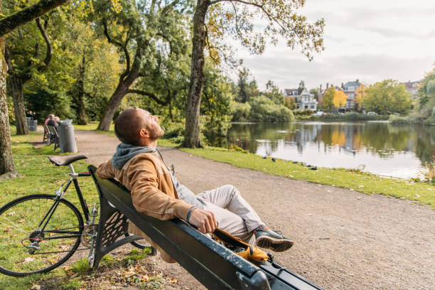 istock Man with a bicycle sitting on public park bench in Amsterdam 2188633670