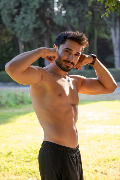 istock Young man showing muscles in a park 2188639833