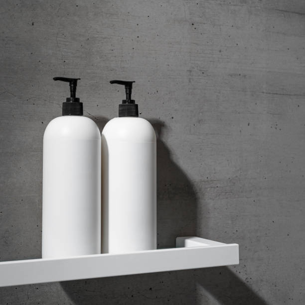 istock Two minimalist white bottles with black pump caps on white shelf against texture gray concrete background. Neutral tones minimalist interior design bathroom. Skincare, body care, beauty products 2188649260