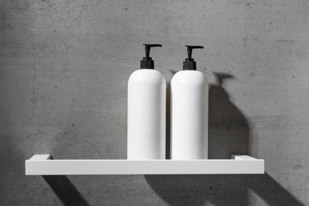 istock Two minimalist white bottles with black pump caps on white shelf against texture gray concrete background. Neutral tones minimalist interior design bathroom. Skincare, body care, beauty products 2188649267