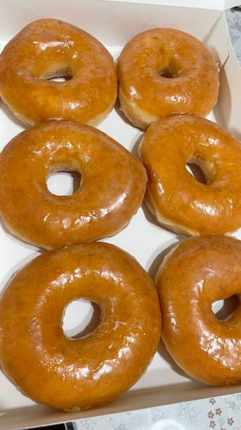 istock A classic glazed donut with a soft, fluffy texture and a sweet, glossy coating. Perfectly balanced between light and sugary, making it an irresistible treat for any time of the day. 2188649466