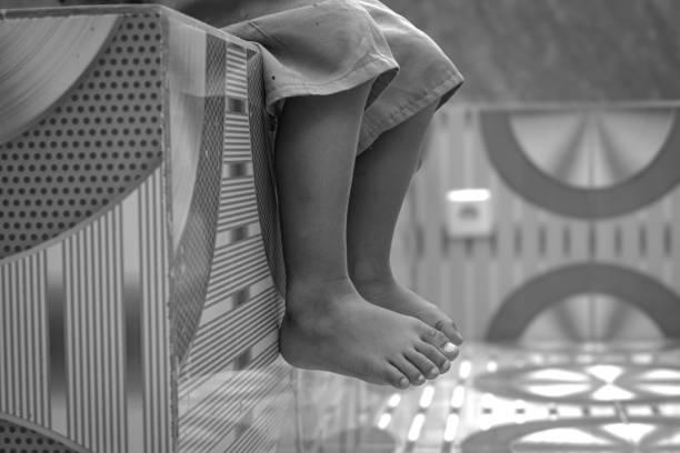 The feet of a boy sitting on a ceramic bench