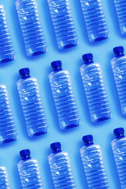 istock Clear single-use plastic water bottles for water on light blue background close-up geometric pattern, minimal style object, top view row bottle, Pollution, environmental protection, plastic waste 2188651178