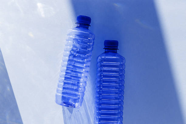 istock Clear plastic water bottles for clean water on white blue background closeup, minimal aesthetic lifestyle photo, top view, flat lay, Naural light, sunlight shadows, caustic light effect, star filter 2188651185