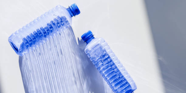 istock Clear plastic water bottles for clean water on white blue background closeup, minimal aesthetic lifestyle banner, top view, flat lay, Naural light, sunlight shadows, caustic light effect, star filter 2188651188