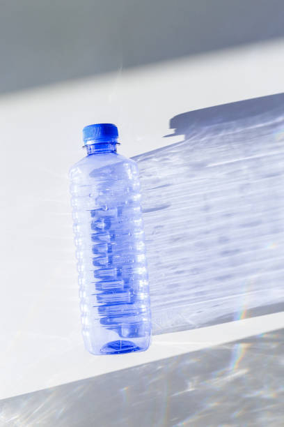 istock Transparent plastic bottles with blue caps and sun shadows on light background. Top view Water bottles at natural light. Themes of recycling, sustainability, water conservation, minimal style 2188651190