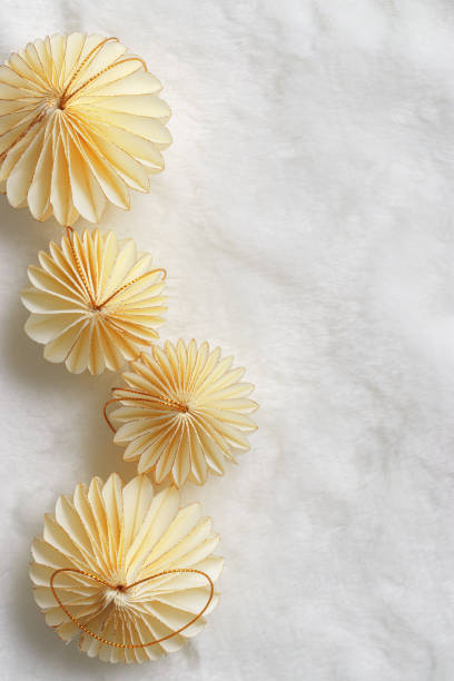istock New Year decorative ornaments, golden Christmas flashlights shape bauble on white fur with soft folds background, Minimal layout with paper festive decor beige balls, modern decor, top view 2188652421