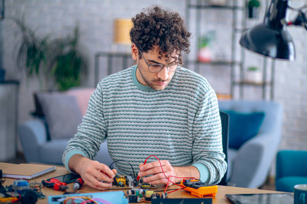 Man testing the parts on the circuit boards with multimeter