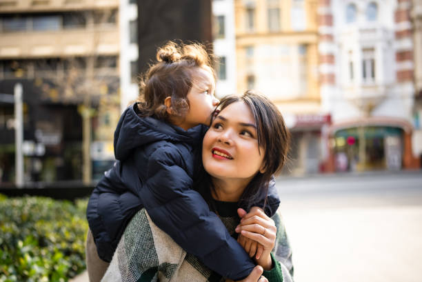 istock son standing behind mother, arms around neck, smiling 2188664074