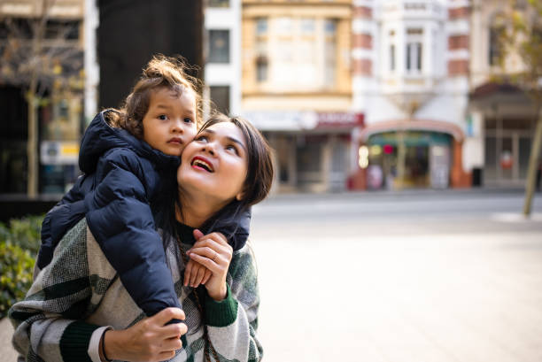 istock son standing behind mother, arms around neck, smiling 2188664101