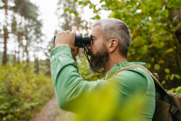 istock Handsome man watching wildlife with binoculars, enjoying peaceful atmosphere of forest, forestbathing 2188664940