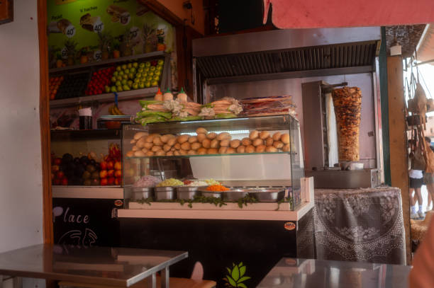 Vibrant food stall showcasing a rotating shawarma, an assortment of bread, and colorful fresh ingredients