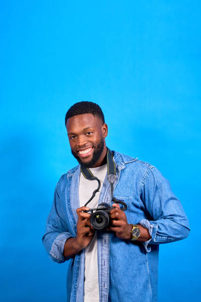 istock Photographer smiling and holding camera on blue background 2188669749