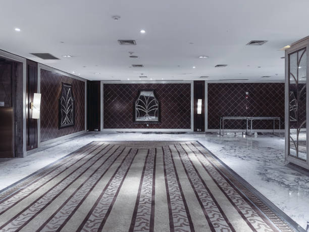 istock A modern and elegant hotel lobby or event corridor featuring luxurious marble flooring, decorative mirrored panels with art deco patterns, soft ambient lighting, and minimalist cocktail tables. 2188669757