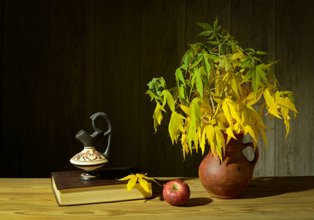 Side view of rustic photo album, cup with beverage and dehydrated fruit on top of a beige fabric with pumpkins on the backgroung.